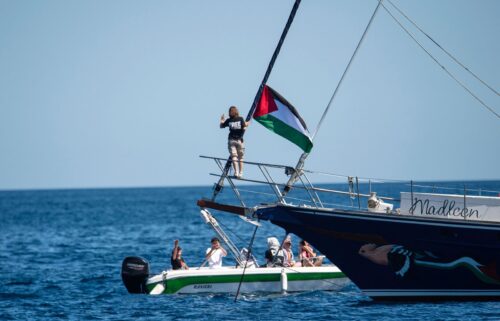 Climate activist Greta Thunberg stands next to a Palestinian flag after boarding the Madleen and before setting sail for Gaza with the Freedom Flotilla Coalition