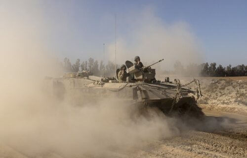 Israeli soldiers stand on an armored personnel carrier as they move near the border with the Gaza Strip as seen from a position on the Israeli side of the border